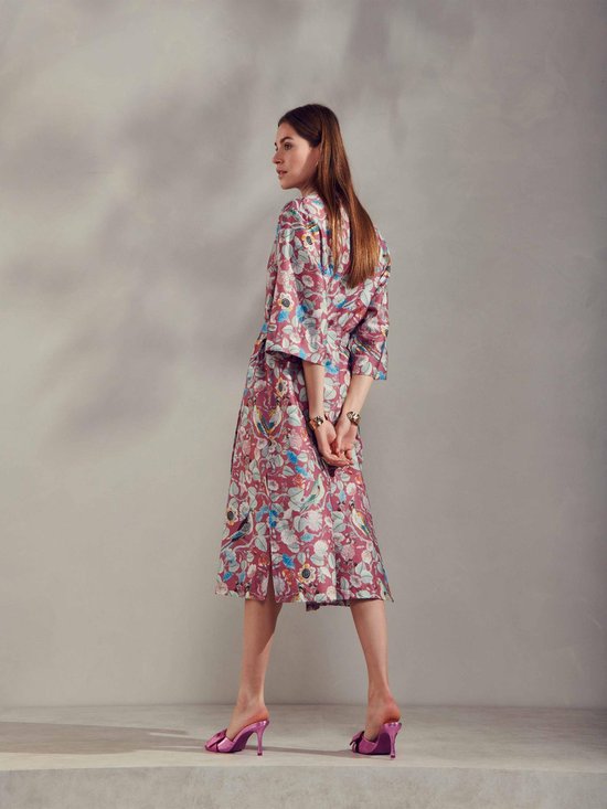 Vrouw in paarse kimono met bloemen- en vogelprint, ceintuur in de taille, driekwart mouwen.