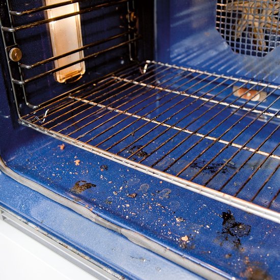 Binnenkant van een vuile oven met blauwe wanden en een grillrooster met vetresten.
