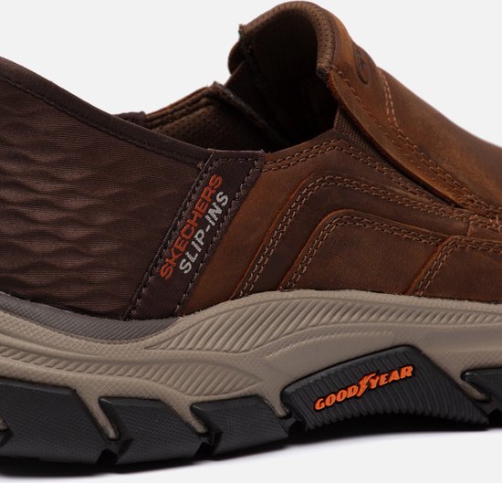 Detail van bruine Skechers Slip-ins met Goodyear zool en oranje 'Slip-ins' logo.