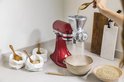 Rode KitchenAid keukenmachine met graanmolen, met zakken vol graan ernaast.