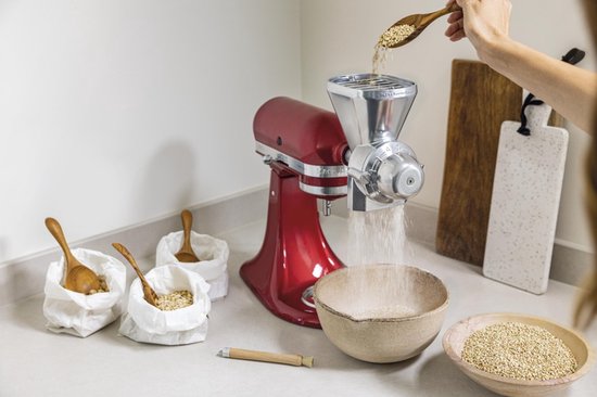Rode KitchenAid keukenmachine met graanmolen, met zakken vol graan ernaast.