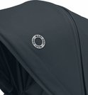 Close-up van het donkerblauwe Maxi-Cosi logo op de kap van de kinderwagen.