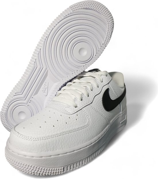 Witte Nike Air Force 1 sneaker met zwarte swoosh, met de zool omhoog.
