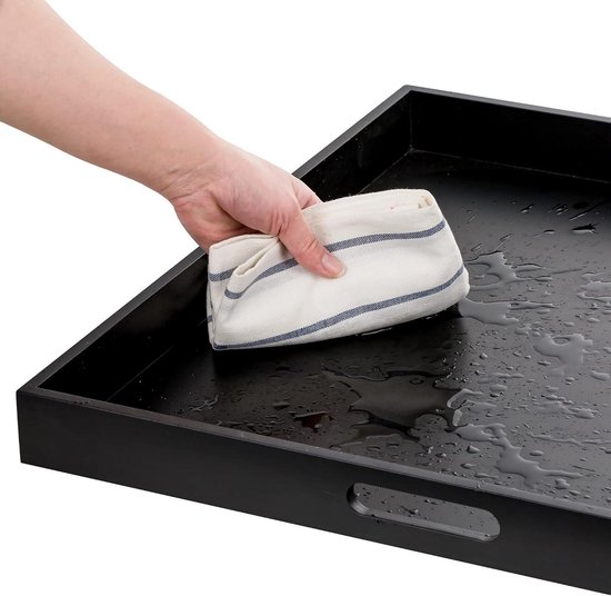 Hand die een zwart dienblad schoonmaakt met een gestreepte doek.
