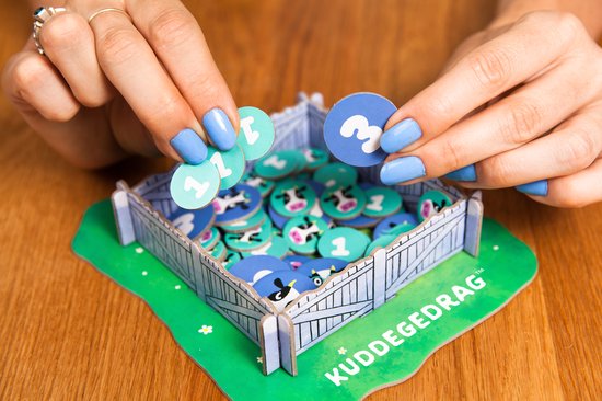 Vrouw met blauwe nagellak houdt koe-tokens vast in het spel Kuddegedrag.