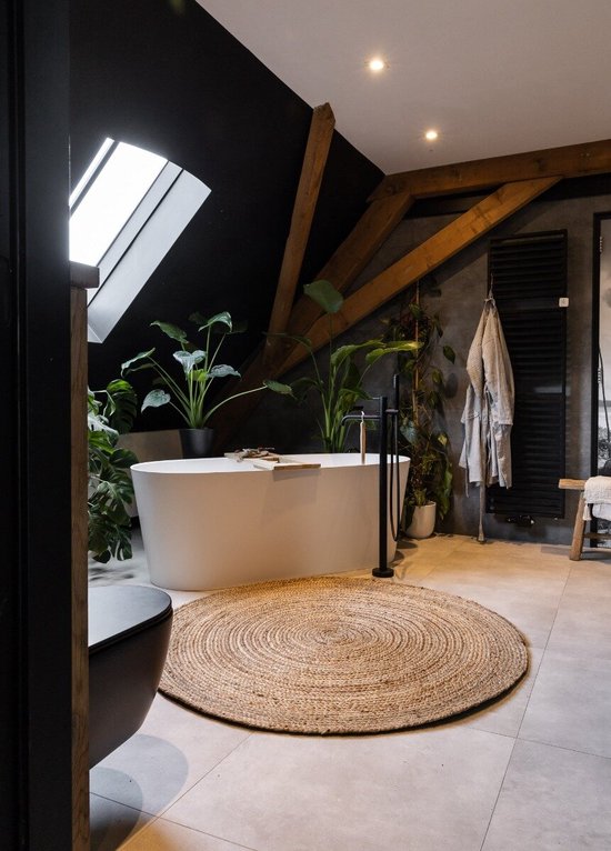 Een rond, natuurlijk jute vloerkleed in een moderne badkamer met een vrijstaand bad.