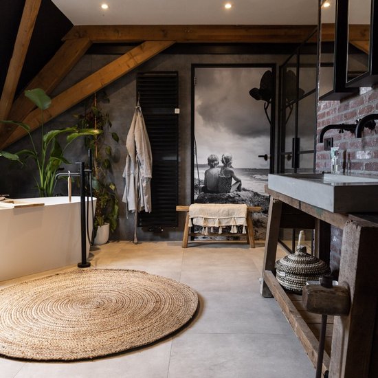Rond, natuurlijk jute vloerkleed met cirkelpatroon in een sfeervolle badkamer.