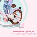 Kind op een roze fiets met zijwieltjes en tekst 'Afneembare zijwieltjes'.
