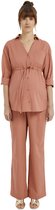Model met oranje zwangerschapsblouse en bijpassende wijd uitlopende broek, gedragen met gouden sandalen.