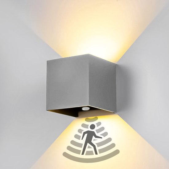 Grijze XEOD wandlamp met sensor die licht uitstraalt naar boven en beneden op een witte muur.