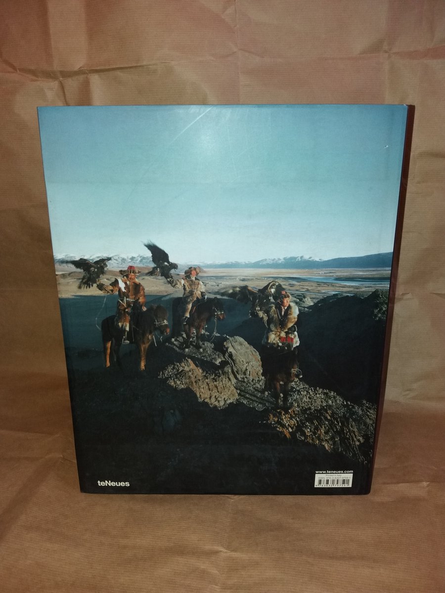 Achterkant van een boek met een afbeelding van mannen te paard met adelaars in een berglandschap.