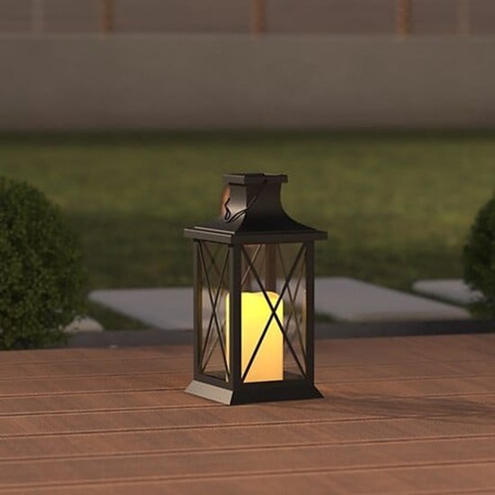 Zwarte lantaarn met brandende LED-kaars, geplaatst op een houten dek buiten.