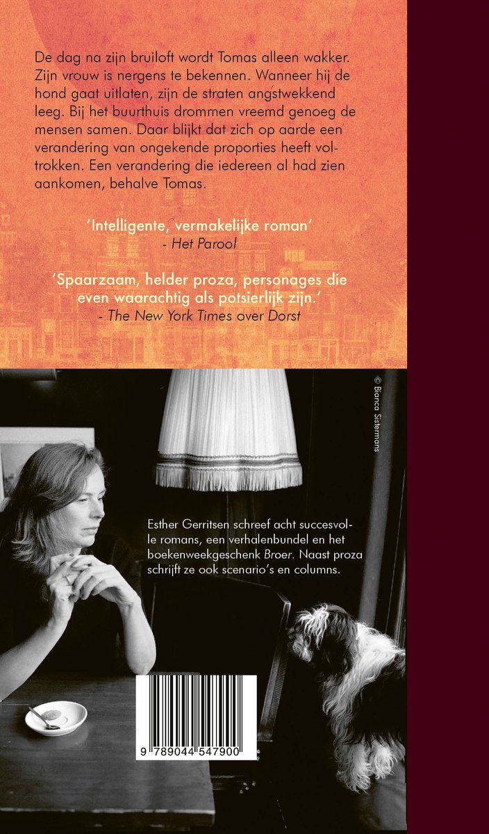 Een vrouw met bruin haar, gekleed in een zwart vest, zit aan een tafel met een hond op de achtergrond. Boekkaft met tekst.