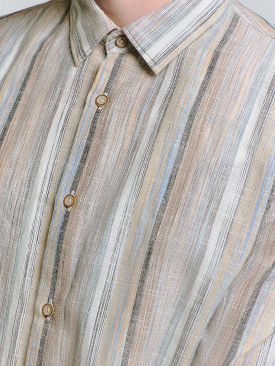 Close-up van een beige overhemd met verticale strepen in bruin, blauw en grijs. Bruine knopen.