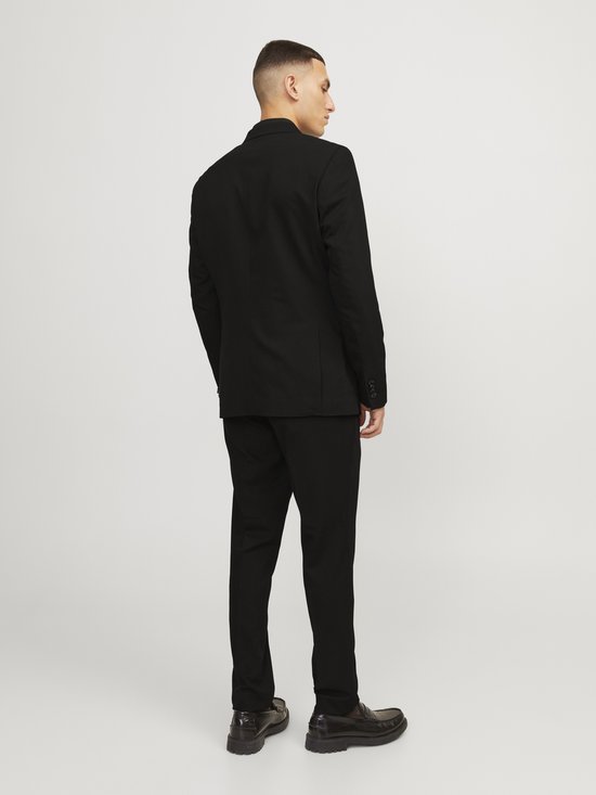 Man in volledig zwart JACK & JONES pak, gezien vanaf de achterkant. Blazer met meerdere knopen op de mouw.