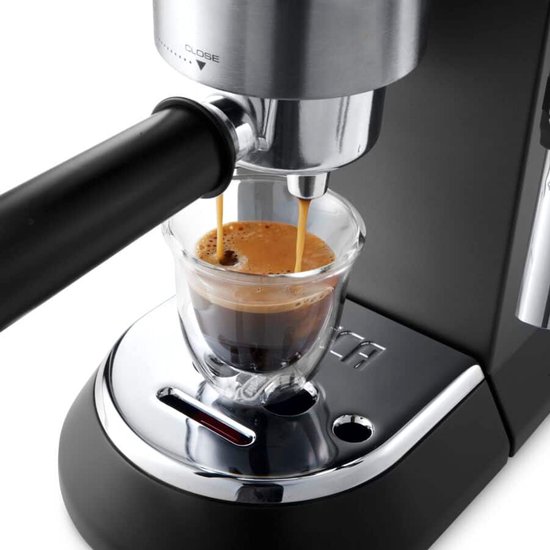 Close-up van een zwarte De'Longhi pistonmachine die espresso in een dubbelwandig glazen kopje zet.