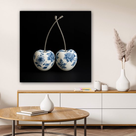 Delfts blauwe kersendecoratie aan de muur boven een dressoir in een lichte woonkamer.