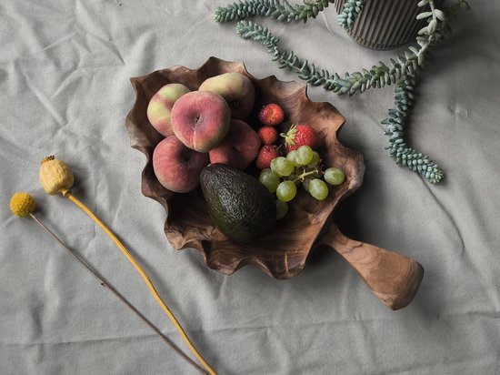 Houten fruitschaal met gegolfde rand, gevuld met perziken, aardbeien, avocado en druiven.