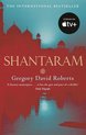 Boekomslag van Shantaram door Gregory David Roberts. Rode silhouetten van gebouwen en reflecties op water, met de titel en "THE INTERNATIONAL BESTSELLER".