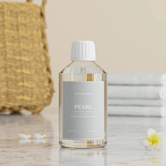 Fles Steamstory wasparfum 'Pearl' op een marmeren ondergrond met een mand en bloemen.