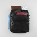 Zwarte leren tas met paspoort, sleutels, telefoon, portemonnee en blauwe pen.