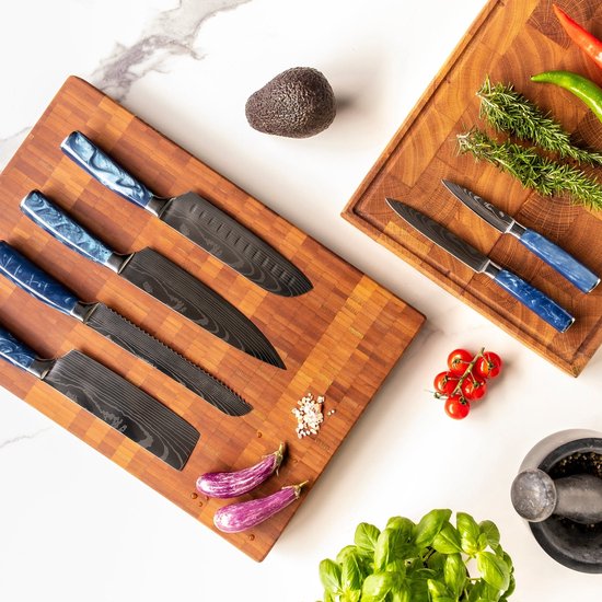 Set van 5 damast gesmede messen met blauwe epoxy handvatten op houten snijplank, met aubergines en tomaten.