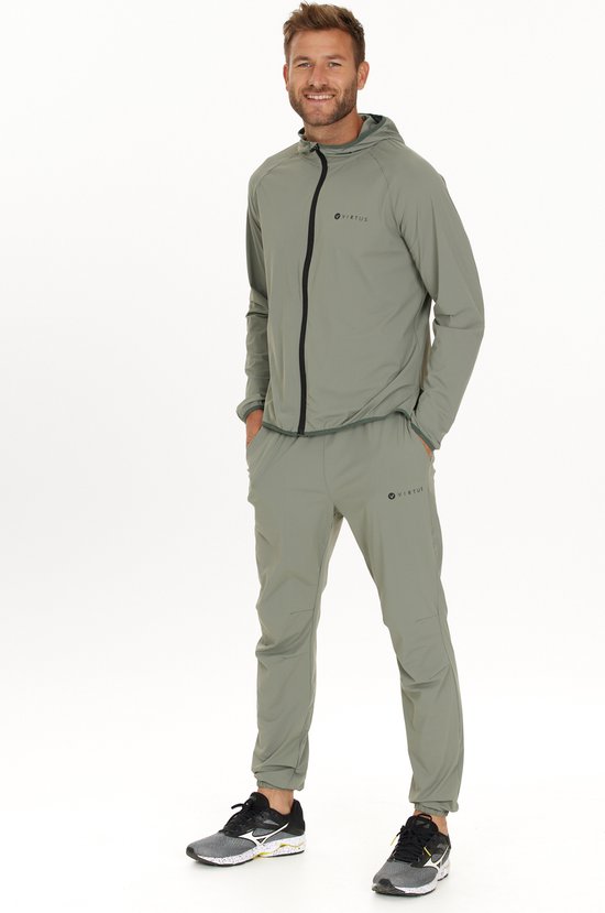 Man in een grijze sportoutfit bestaande uit een trainingsjack met capuchon en een sportbroek.