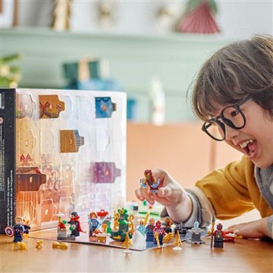 Jongen met bril speelt met LEGO Marvel Avengers Adventskalender figuren op tafel.