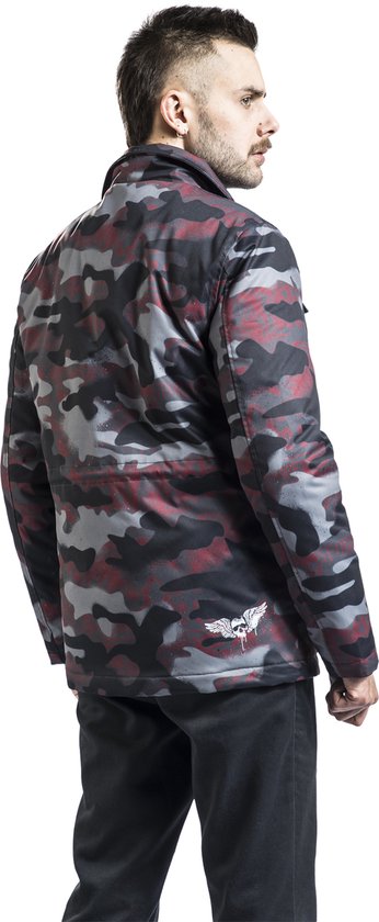Man met rug naar de kijker, draagt jas met camouflageprint in grijs, zwart en rood, met gevleugelde doodskop op de rug.