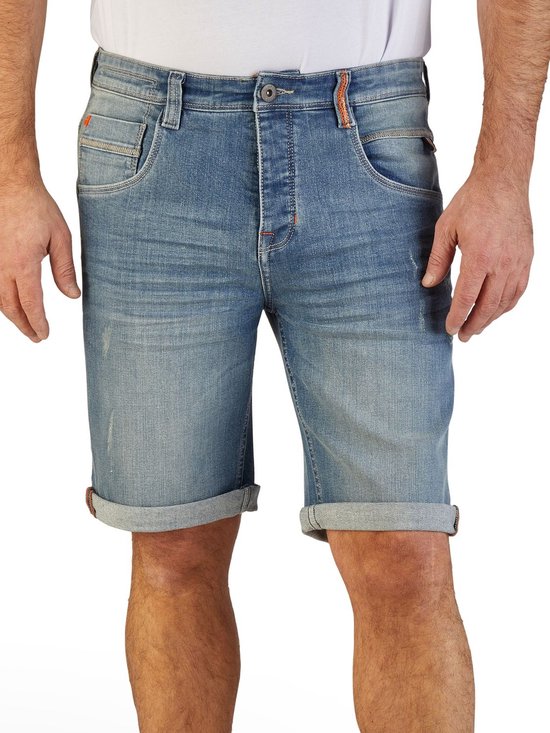 Man draagt blauwe denim short met omgeslagen broekspijpen en lichte wassing.