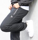 Model in een zwarte joggingbroek, met witte sneakers.