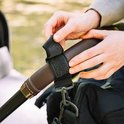 Mains attachant un clip noir pour poussette au guidon d'une poussette.