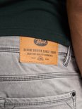 Close-up van het bruine leren Petrol Industries label op de achterkant van een grijze denim short. De tekst 'DENIM DRIVEN SINCE 1989' is zichtbaar.