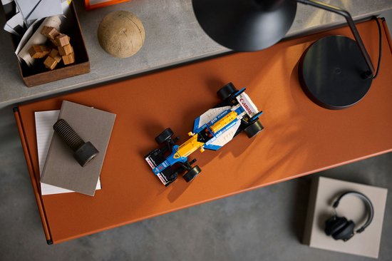 LEGO Williams FW14B auto op een bruin bureau, met een lamp en koptelefoon.