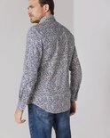 Man van achteren gezien, draagt een blauw overhemd met een print van witte, bruine en donkerblauwe lijntjes. Jeans erbij.