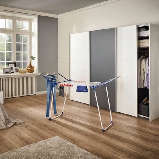 Un étendoir Leifheit Pegasus avec un pantalon suspendu dans une chambre.