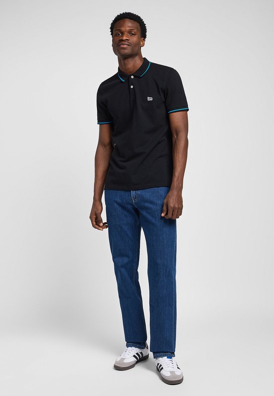 Model in donkerblauwe Lee jeans met rechte pijpen en zwarte polo met blauwe details.