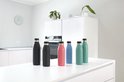 Zes thermosflessen op een wit aanrecht: zwart, roze, blauw en teal.