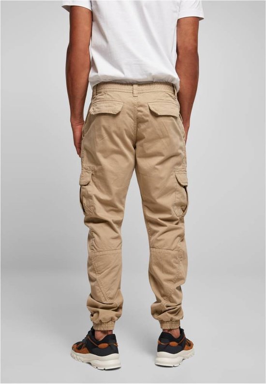 Man met beige cargo broek, achterkant zichtbaar, met zakken en elastische enkelbanden.