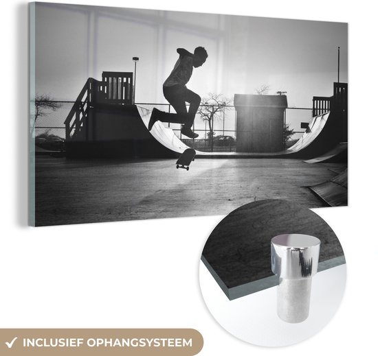 MuchoWow® Glasschilderij 40x20 cm - Schilderij acrylglas - Een jongen doet een stunt met zijn skateboard tijdens de zonsondergang - zwart wit - Foto op glas - Schilderijen