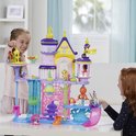 Twee meisjes spelen vrolijk met een paars, roze en geel My Little Pony kasteel.