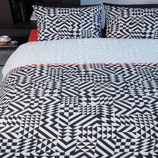 Un lit avec une housse de couette et des oreillers au motif géométrique noir et blanc avec des accents rouges.