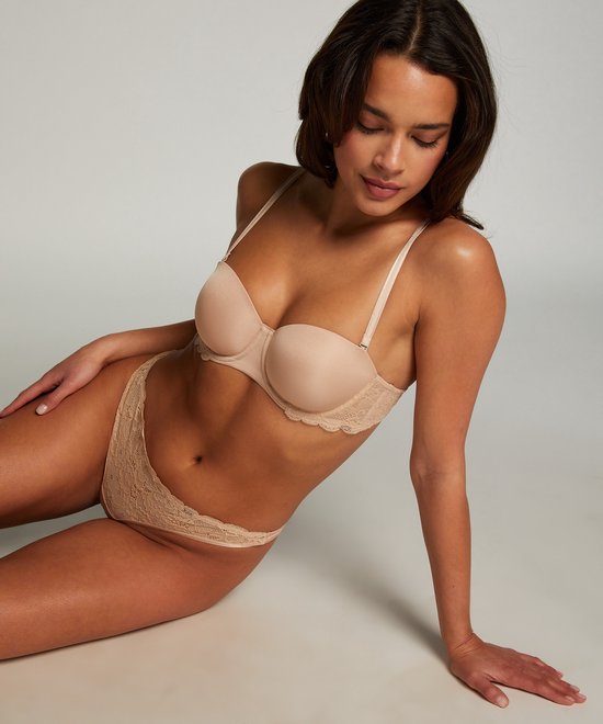 Beige strapless beha met kanten details. Model draagt de beha.