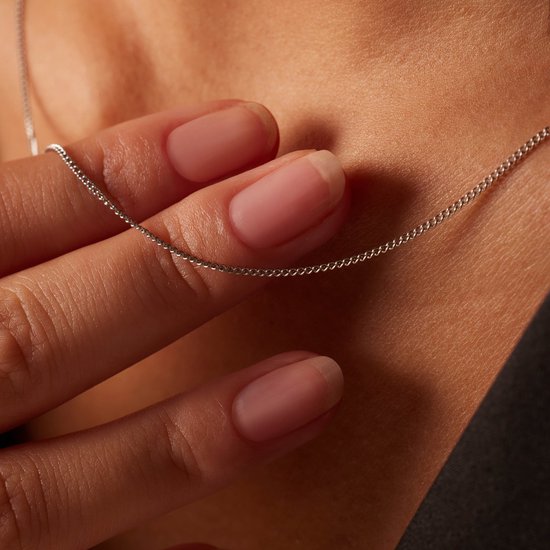 Close-up van een zilverkleurige gourmet ketting van 1mm breed gedragen door een model.