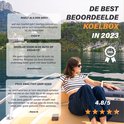 Een vrouw met een gestreepte top en zonnebril zit op een boot met een blauwgrijze koelbox.