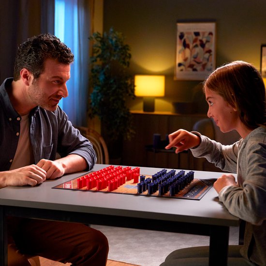 Een vader en dochter spelen Stratego, met het speelbord vol rode en blauwe pionnen op tafel.