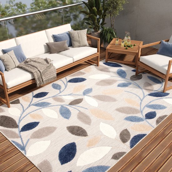 Balcon avec un tapis à motif de feuilles bleues, grises, crème et beiges, avec des meubles d'extérieur blancs.