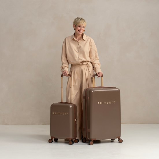 Vrouw met blonde bob met twee bruine SUITSUIT koffers in een lichte studio.