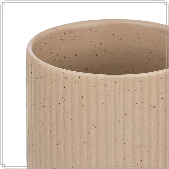 Détail d'une tasse blanc cassé à motif côtelé et moucheté de brun.