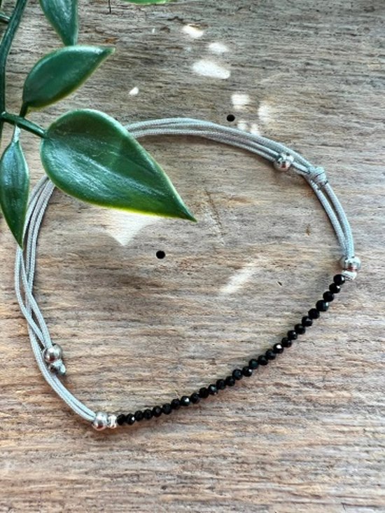 Zwarte facet geslepen kristallen armband met zilverkleurig koord en knopen.